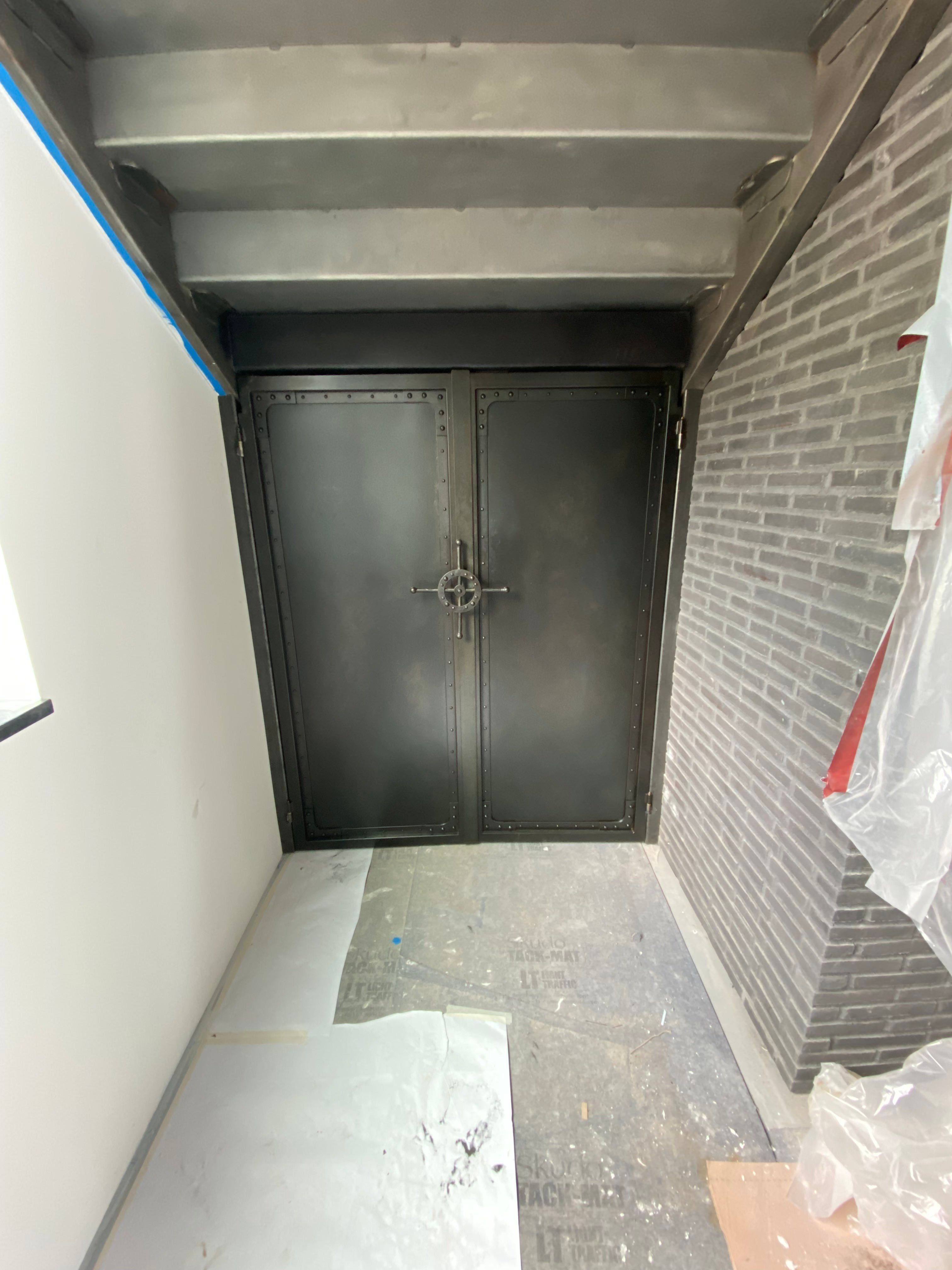 Custom forged vault door with heavy steel frame and decorative hardware